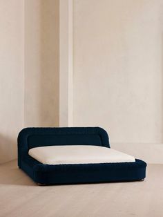 a blue couch sitting on top of a wooden floor next to a white wall and window