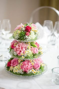 three tiered cake decorated with pink and white flowers on top of a round table