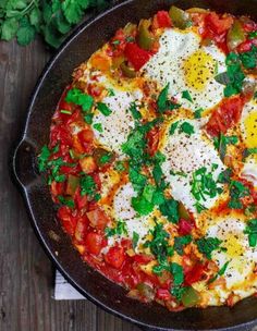 an omelet with eggs and tomatoes in a cast iron skillet on a wooden table