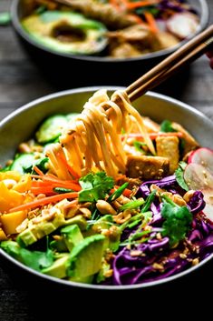 two bowls filled with salad and chopsticks on top of the bowl, next to each other