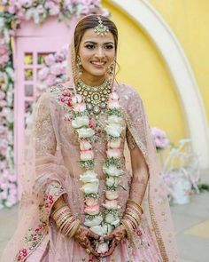 a woman in a pink lehenga with flowers around her neck