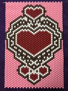 a pink and black beaded artwork with a heart on it