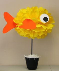 a paper flower with a fish on it sitting next to a black potted plant