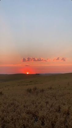 the sun is setting over an open field