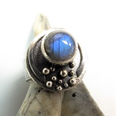 "Moon ring in sterling silver with a large and luminous labradorite cabochon. A statement ring with a lunar theme and interesting textures, elements. This is a nice weighty ring with solid heft and a wide hammered band. A bit rustic, a bit refined and sure to capture your gaze with the deep blue flash labradorite.  Size 7.75 but can be sized up to an 8. Top of ring measures 3/4\" wide or almost 20mm. Labradorite is 10mm and the band is 7.5mm wide. Metalsmith jewelry by Mocahete is built using tr Unique Sterling Silver Moonstone Cabochon Ring, Unique Silver Moonstone Ring, Unique Silver Cabochon Moonstone Ring, Unique Silver Moonstone Ring With Cabochon, Unique Moon Phase Rings, Metalsmith Jewelry, Lunar Jewelry, Interesting Textures, Metalsmithing Jewelry