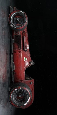 an old race car hanging from the side of a black wall with red paint on it