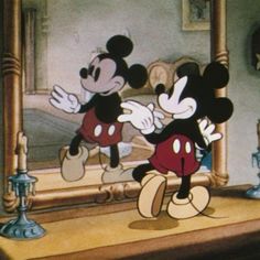 mickey and minnie dancing in front of a mirror