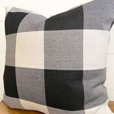 a black and white checkered pillow sitting on top of a wooden table next to a wall