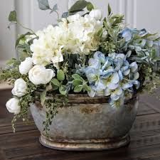 white and blue flowers are in an old metal bowl