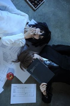 a person laying on the ground with papers and an apple in front of her face