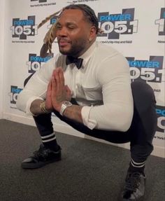 a man in white shirt and black pants sitting on the floor with his hands crossed