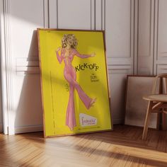 a yellow poster with a woman in a pink dress is on the floor next to a chair