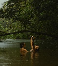 two people are in the water and one is reaching up for something