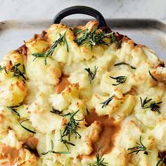 a casserole dish with potatoes and herbs on top, ready to be eaten