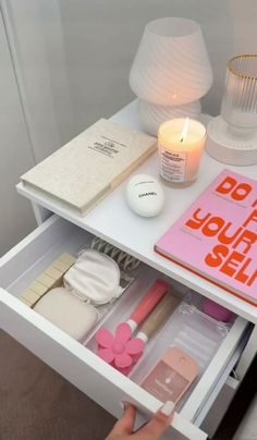 a white table topped with lots of items and a pink book sitting on top of it