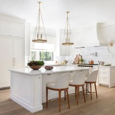 a large kitchen with white cabinets and wooden flooring, along with an island in the middle