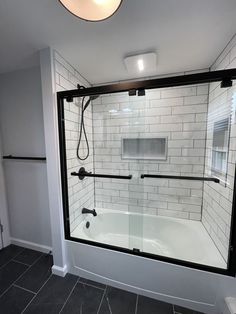 a bathroom with a glass shower door and tile flooring on the walls is shown