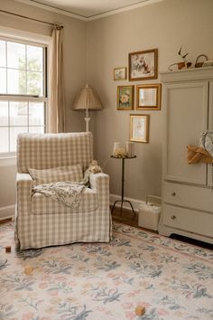 a living room filled with furniture and framed pictures on the wall behind a chair in front of a window