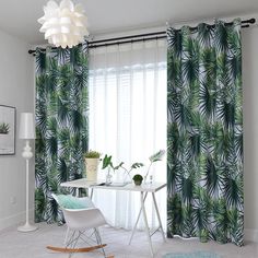 a living room filled with furniture and green palm leaves on the curtained drapes