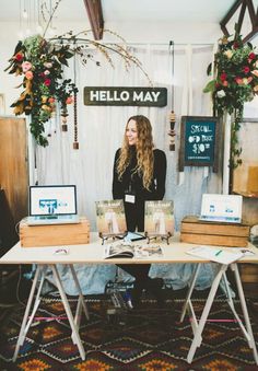 a woman standing behind a table with laptops on it