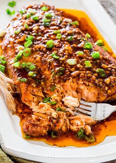 salmon with sesame seeds and green onions served on a white platter, ready to be eaten