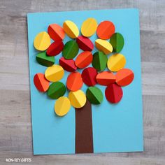 a tree made out of colored paper sitting on top of a wooden table