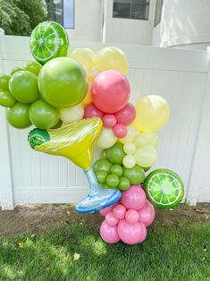 a bunch of balloons that are in the grass with some fruit on top of them