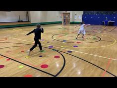 two young boys are playing basketball on an indoor court with colored circles around them and one boy is about to hit the ball