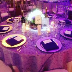 the table is set with purple linens and place settings