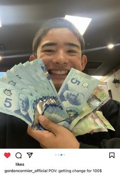 a man holding up five bills in front of his face and smiling at the camera