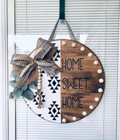 a wooden sign that says home sweet home hanging on the front door with a bow