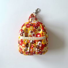 a small purse hanging from a hook on a white wall with flowers all over it