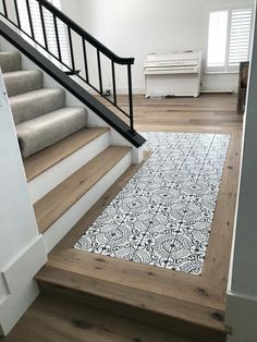 a white and black rug on the floor next to some stairs in an empty room