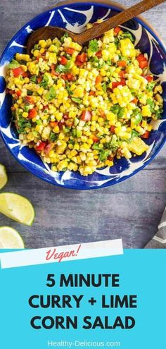 a blue bowl filled with corn salad next to sliced limes and a wooden spoon