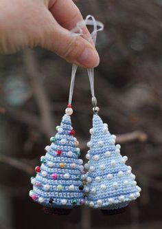 someone is holding two christmas trees made from beads