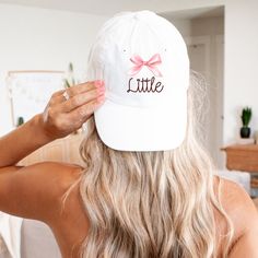 a woman wearing a white hat with a pink bow on the front and back of her head