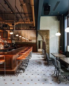 an empty restaurant with tables and bar stools in front of the counter, along with hanging lights