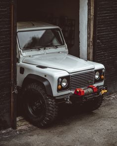 a white jeep parked in front of a brick building next to a red fire hydrant