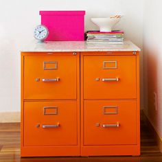 an orange filing cabinet with a clock on top