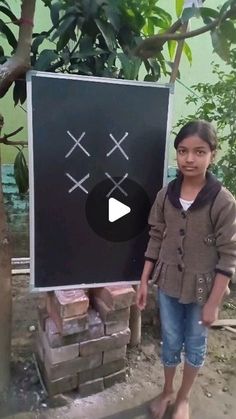 a girl standing in front of a sign with crosses drawn on it