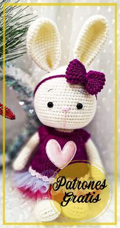 a crocheted bunny with a heart on it's chest sitting next to a christmas tree