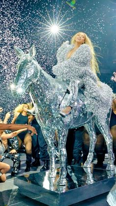 lady on top of a silver horse statue surrounded by confetti and sparkles