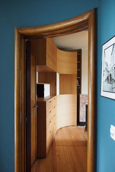 a room with blue walls and wooden floors is shown through an arch shaped doorway that leads to the bedroom