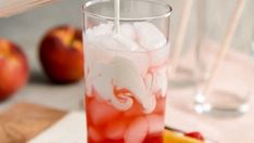 a glass filled with ice and fruit on top of a table