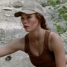 a woman with blood on her face is holding a tennis racquet in front of a waterfall