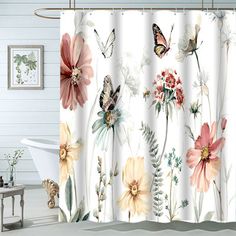 a white bath tub sitting next to a shower curtain with flowers and butterflies on it