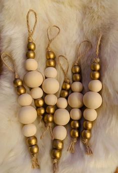 several wooden beads are hanging from twine on a white fur covered surface with gold colored balls