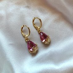 A beautiful pair of either blue or pink glass gem earrings with gold floral detailing. These gems sit on 14k gold filled huggie hoops. This piece comes with a velvet gift bag. Making them ideal as a gift or a treat to yourself.For this piece the huggie hoops are 14k gold filled with a copper core. The hoops use a lever back for closure. The inner diameter of the hoop is 1cm. The gems used in this piece are made of glass and are frame with flowers made with gold plating. Pink Gold-plated Jewelry Tarnish Resistant, Pink Gold-plated Tarnish-resistant Jewelry, Tarnish Resistant Pink Gold Plated Jewelry, Pink Tarnish Resistant Gold Plated Jewelry, Pink Tarnish-resistant Gold-plated Jewelry, Pink Dainty Huggie Earrings, Dainty Pink Huggie Earrings, Pink Cubic Zirconia Hoop Earrings For Gift, Pink Cubic Zirconia Hoop Earrings As Gift