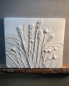 a white tile with flowers on it sitting on a shelf