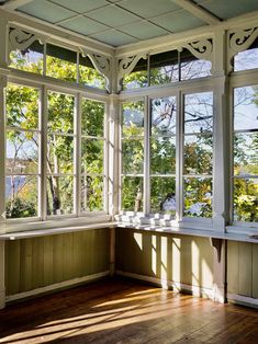 the sun shines through two windows in an empty room with wood floors and walls